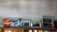 Photo of boxed toy vehicles including Coca-Cola truck, Classic Trucks set, and three Vintage Vehicle by Ertl boxed models on a shelf.