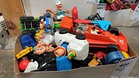 Box with assorted vintage toy vehicles and figures including parts of a red and blue Tonka racing car with driver figure and assorted toy car parts.
