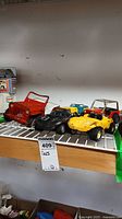 Shelf display showing five vintage toy vehicles including red jeep, dune buggies