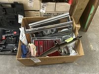 Box of vintage car light housings and exterior parts showing front bezels, red tail light assembly, and rusty bracket.