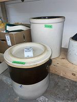 Two vintage stoneware crocks on a wooden shelf showing their size and external condition