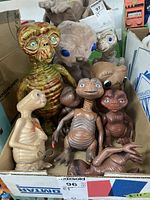Box containing multiple vintage E.T. dolls and figurines of varying materials and sizes from 6 to 12 inches tall