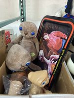 Two vintage E.T. plush dolls, small plastic E.T. figure, and metal tray in a box