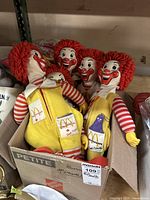 Five vintage Ronald McDonald dolls in box with yellow overalls and brass feet supports