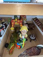 Photo of vintage toys including pull toys, plush animals, dolls, and wind-up fish arranged in cardboard box