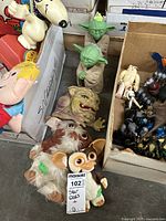 Photo showing multiple Yoda figures, several Gremlins dolls, and a Boglin rubber puppet arranged together on floor.
