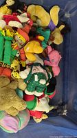 Close view of mixed plush toys inside blue mesh bin
