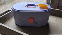 Closed case front view showing lavender body, pink latch, Caboodles logo