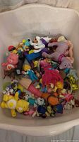 Tub containing assorted small plastic figurines