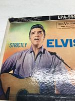 Front album cover featuring a large photo of Elvis Presley wearing a striped shirt and holding a guitar. Album title and RCA Victor branding present.