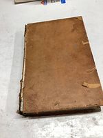 Photo of the front cover showing worn leather surface with signs of staining and damage at edges.