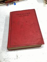 Front hardcover of the 1924 Treasure Island book, showing red cloth cover with title printed on it.