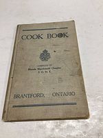 Front cover of the cloth-bound cookbook showing title, compiler and location.