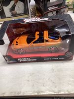 Front view of the orange diecast Toyota Supra model in unopened Fast and Furious packaging.