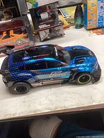 Blue New Bright Ford racing style remote control car with geometric patterns and Ford branding, shown from side angle.