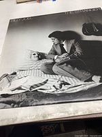 Photo of the Billy Joel The Stranger vinyl record album cover showing artwork with a man sitting beside a masked person in bed.