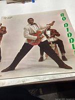 Front cover of the Bo Diddley album showing Bo Diddley playing a guitar with band members in the background.