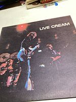 Front cover of the 'Live Cream' vinyl record album showing band members performing on stage.