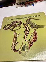 Front cover of vinyl record album 'The Early Animals with Eric Burdon' showing artistic reptile and amphibian illustrations on yellow-green background.