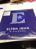 Front cover of a sealed Elton John Diamonds vinyl record showing a large stylized 'E' made of diamond dots and the artist's name below.