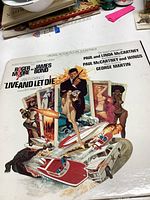 Front cover of the Live and Let Die James Bond soundtrack vinyl record featuring illustrated action and character scenes.