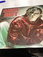 Front cover of Quiet Riot Metal Health vinyl album showing masked figure in red jacket.