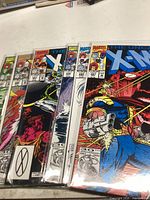 Six X-Men comic books fanned out, showing vibrant covers with various characters including Wolverine.