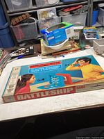 Full view of the vintage Battleship game box on table with surrounding items