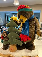 Full front view of the large plush bears and the light-up Christmas tree on white snowy base