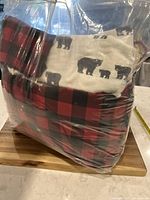 Photo showing the packed bed set with red and black plaid duvet cover and shams along with sheets featuring bear motifs.