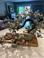 Two bonsai-style stone and jade trees placed on a wooden surface with the larger tree on the right and smaller on the left, showing overall size and color detail.