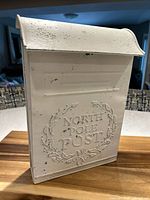 Front view of metal North Pole post box showing embossed text and distressed paint