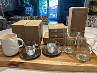 Photo showing all items including latte mugs, espresso cups with saucers, white coffee mug, glasses, and boxed Nespresso Barista accessories.