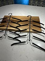 Two metal multi-arm shirt/blouse hangers with padded arms arranged vertically on a countertop.