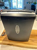 Front view of the Omnitech black paper shredder showing the control buttons and oval transparent window on the front bin.
