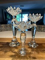 Three clear crystal candleholders showing the front view, highlighting the faceted tops and detailed stems.