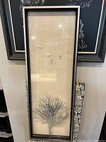 Full view of the vertical shadow box art showing tree and bird outlines on linen background.