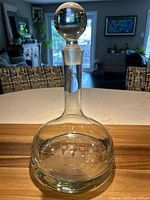 Full front view of the clear glass decanter with spherical stopper, placed on kitchen surface.