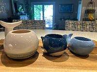 Three whale-shaped planters side-by-side on table showing size and color differences