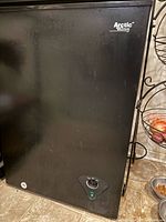 Front view of black Arctic King chest freezer showing minor exterior scratches and brand logo.