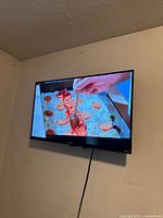 Hisense 32 inch Roku Smart TV wall mounted showing pizza preparation video.