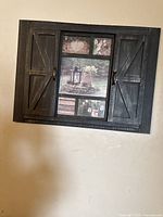 Front view of one rustic barn door style decorative wooden wall frame with multiple photo inserts visible through partially open shutters.