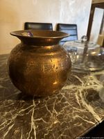 Photo of vintage medium brass pot showing round body and wide flat rim, tarnish and oxidation visible.