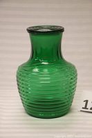 Front view of the forest green glass water bottle showing the horizontal ribs and matching lid