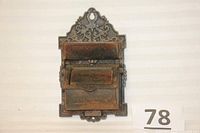 Front view of the antique cast iron match holder showing overall structure with two compartment doors and intricate decorative patterning.