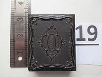 Closed view of the exterior thermoplastic hard case with decorative embossing measuring approximately 3.5 inches tall.