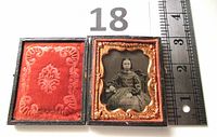 Opened case showing young girl ambrotype photo with ruler for scale