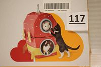 Box front showing the cat scratcher product image shaped like a rocket with two cats interacting with it.