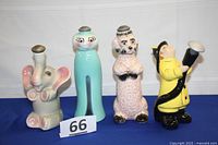Front view of all four ceramic powder sprinklers on blue surface: elephant, clothespin, poodle, fireman