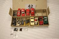 Organizer open showing 4 red slot car Shells on top row, chassis, wheels and four assembled cars in bottom row